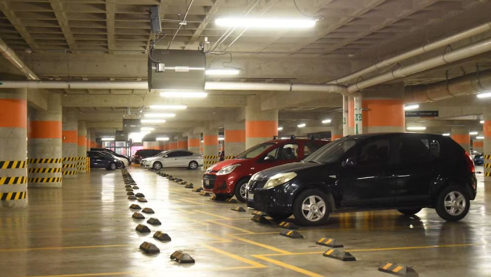 Interior de un estacionamiento subterráneo con vehículos estacionados, nota de Infobae sobre el alquiler de cocheras en Lima